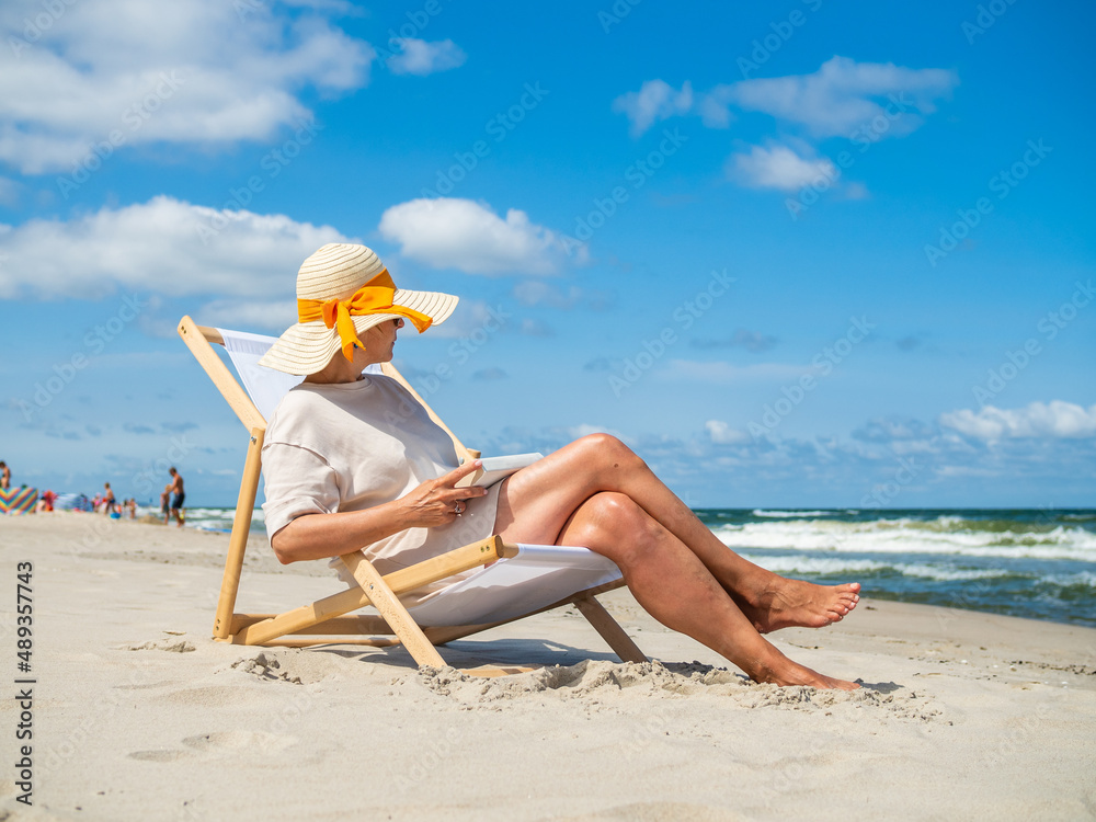 Woman relaxing on beach reading book sitting on sunbed
Woman relaxing on beach reading book sitting on sunbed