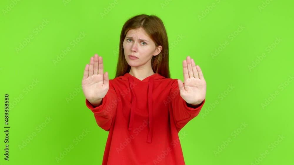 Young woman doing stop sign over isolated background. Green screen chroma key