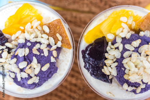 Halo-halo is a popular cold dessert in the Philippines made up of crushed ice, evaporated milk and other toppings. Topped with pinipig and ube , with a straw like wafer added. Top view of two cups. photo