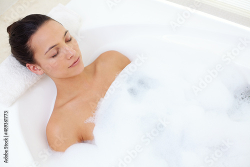 Indulging in a bubble bath. Shot of a beautiful young woman relaxing in the bathtub.