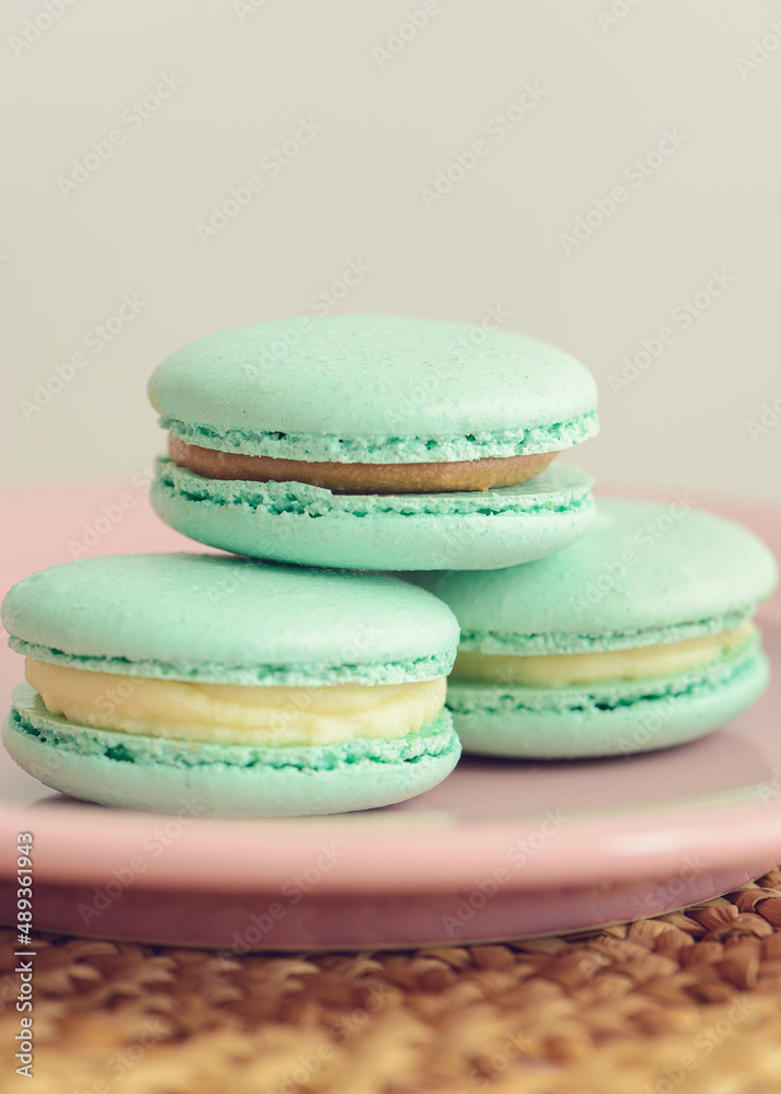 Three green macarons on pink plate. Close-up photo. Vertical photo. Delicious macaroons.