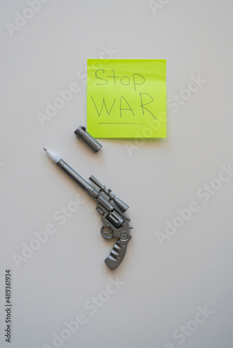 a pen in the form of a pistol lies on a table on a white background. Near the sticker "no war"