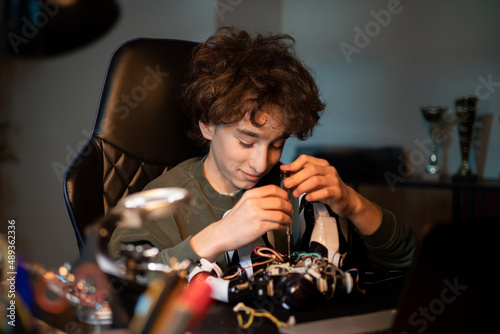 Focused boy fixes robot with screwdriver fixes screws. Above average intelligence of a child interested in electronics, robotics, working on an invention.