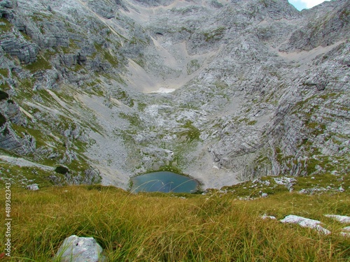 High alpine glacial lake at Kriski podi in Triglav national park and Julian alps in North Littoral region of Slovenia with rocky alpine landscape and a meadow photo