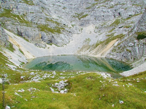 Lower lake at Kriski podi in Triglav national park, Slovenia with a alpine meadow and a scree in the background