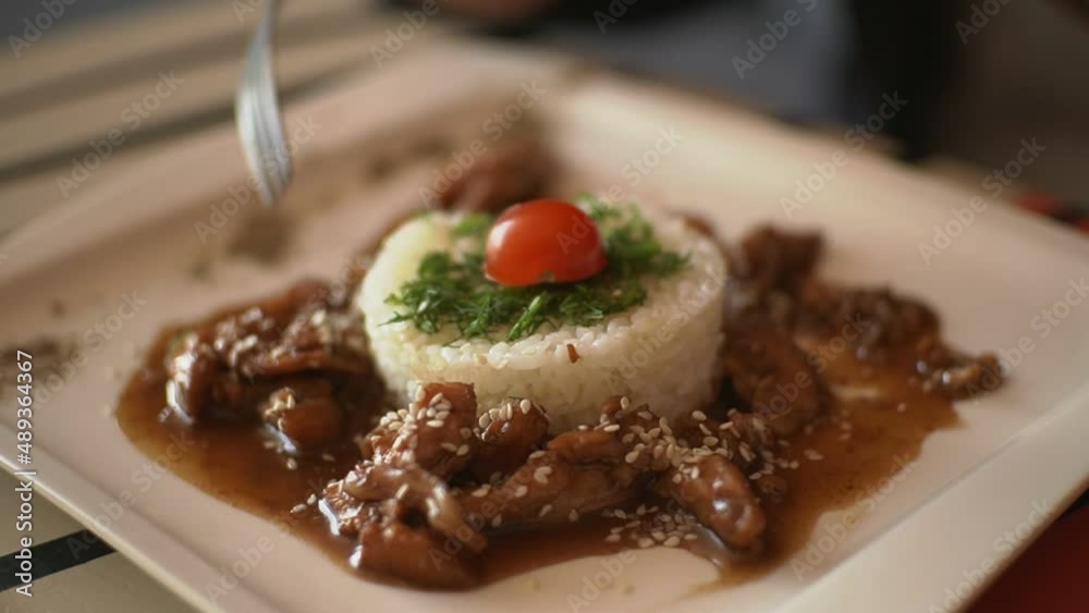 a man in a cafe eats meat and rice using a knife and fork a man in a cafe eats meat and rice using a knife and fork