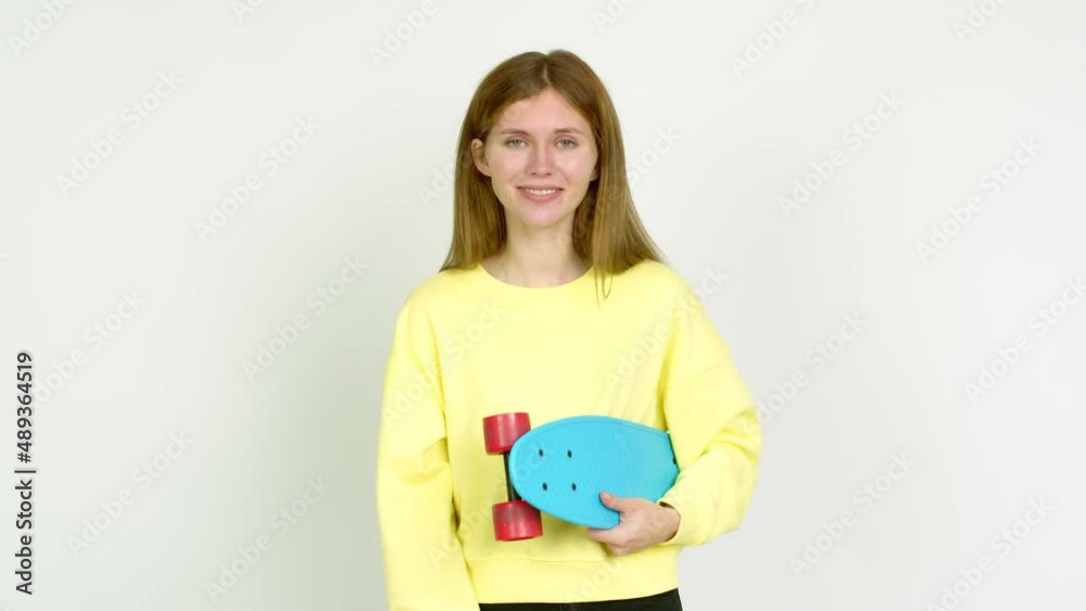 Young woman holding roller skates and  doing surprise gesture over isolated background