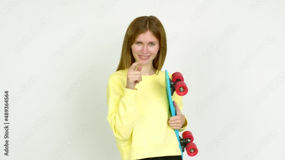 Young woman holding roller skates and doing coming gesture over isolated background Young woman holding roller skates and doing coming gesture over isolated background
