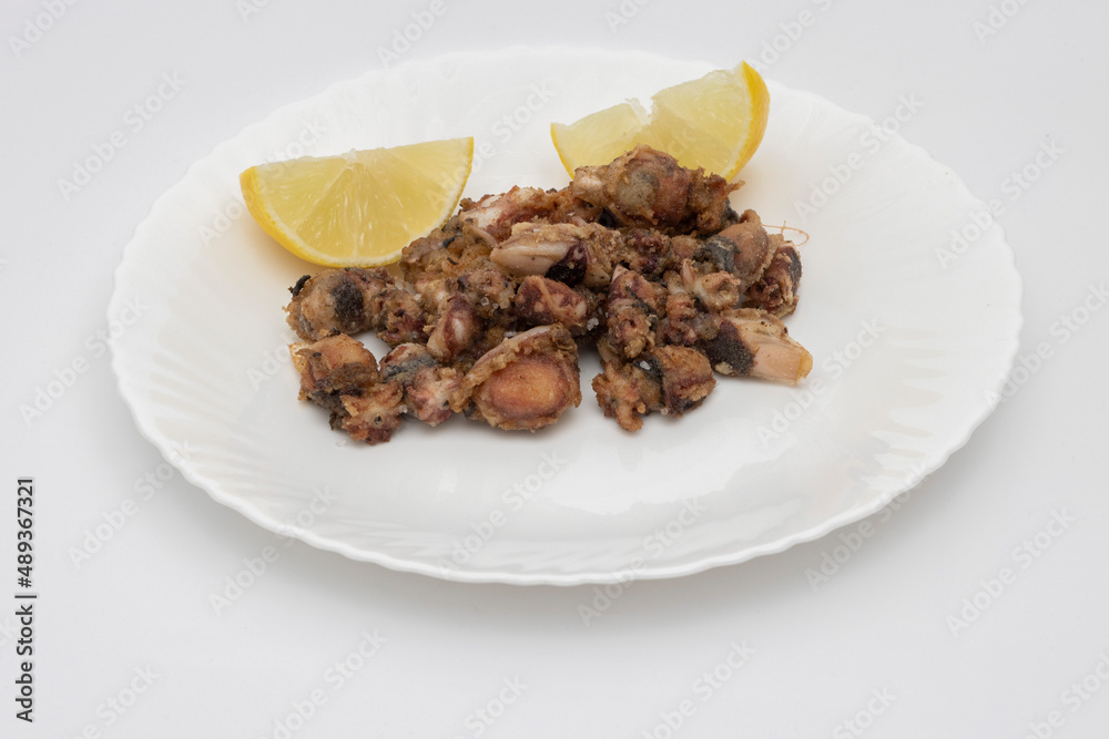 Fried baby squid and two slices of lemons on a white background. Sea food concept.