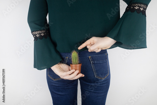 Concept. A woman holds a cactus as a symbol of rectal pain. Varicose veins of the lower intestine. Pain in the rectum, hemorrhoids and pain in the excretory system of the body. Proctology photo