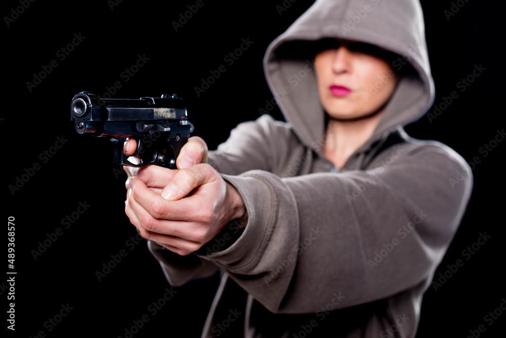 Young woman shooting with gun isolated on black background. Young woman shooting with gun isolated on black background.