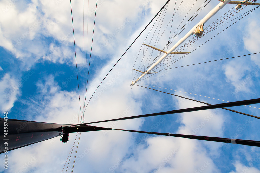 Fototapeta premium Masts of sailing yachts without sails with anchoring ropes. View from below.