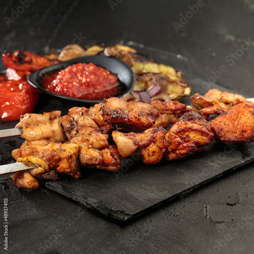 Shashlik or shish kebab preparing on barbecue grill over hot charcoal. Grilled pieces of pork meat on metal skewers. Square image