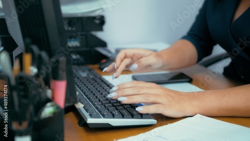 Employee at the computer. The woman types text on the keyboard and presses enter
