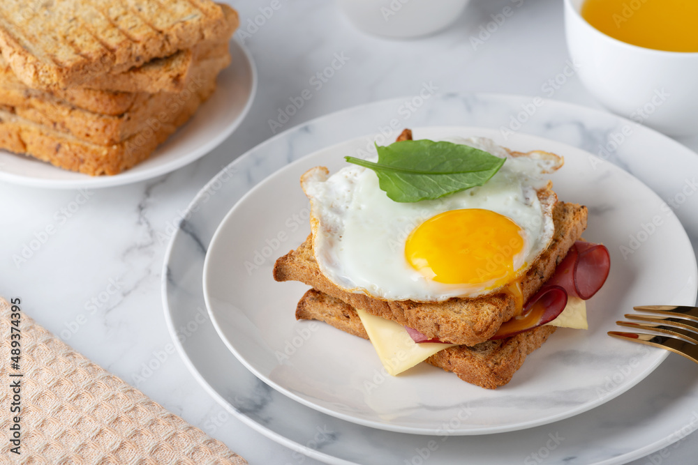 Sandwich with a fried egg, bacon, cheese and spinach