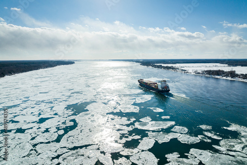 Aerial view of a container ship going upstream through winter ice in the St. Lawrence River near the port of Montreal in Canada