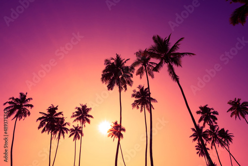 Fototapeta Naklejka Na Ścianę i Meble -  Tropical beach at vivid sunset with coconut palm trees silhouettes and colorful sky