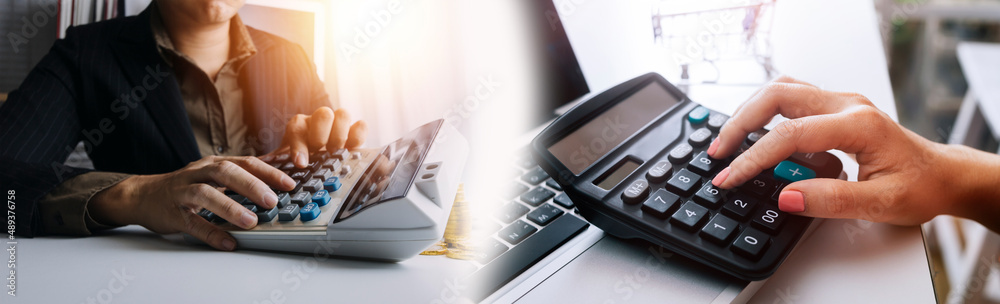 Close up of businessman or accountant hand holding pen working on calculator to calculate business data; accountancy document and laptop computer at office; business concept Close up of businessman or accountant hand holding pen working on calculator to calculate business data; accountancy document and laptop computer at office; business concept