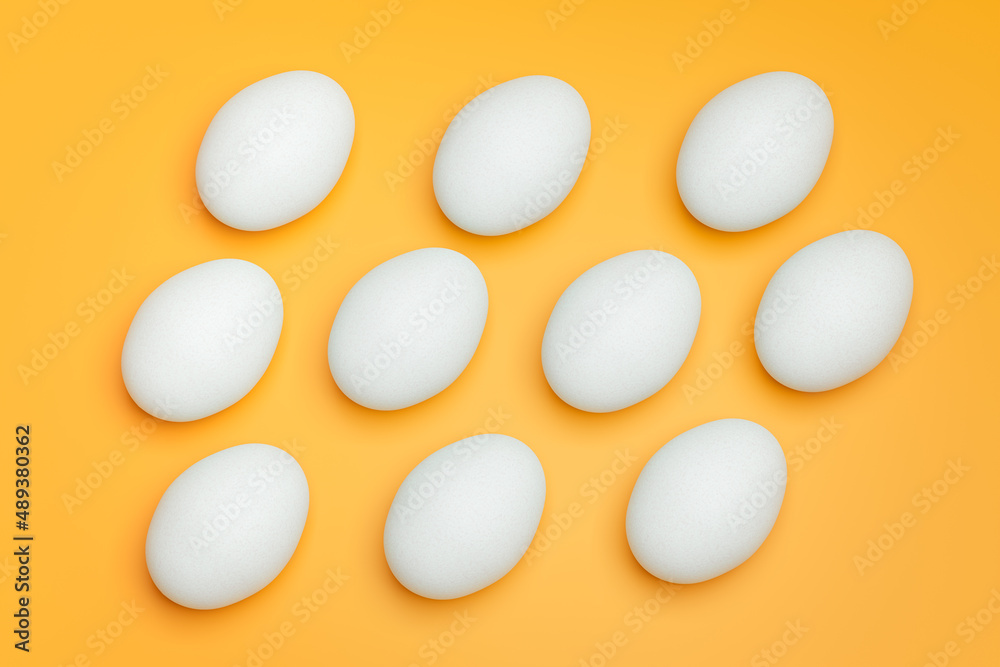 Pattern from white chicken eggs on yellow background top view. Creative food minimalistic background.