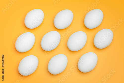 Pattern from white chicken eggs on yellow background top view. Creative food minimalistic background.