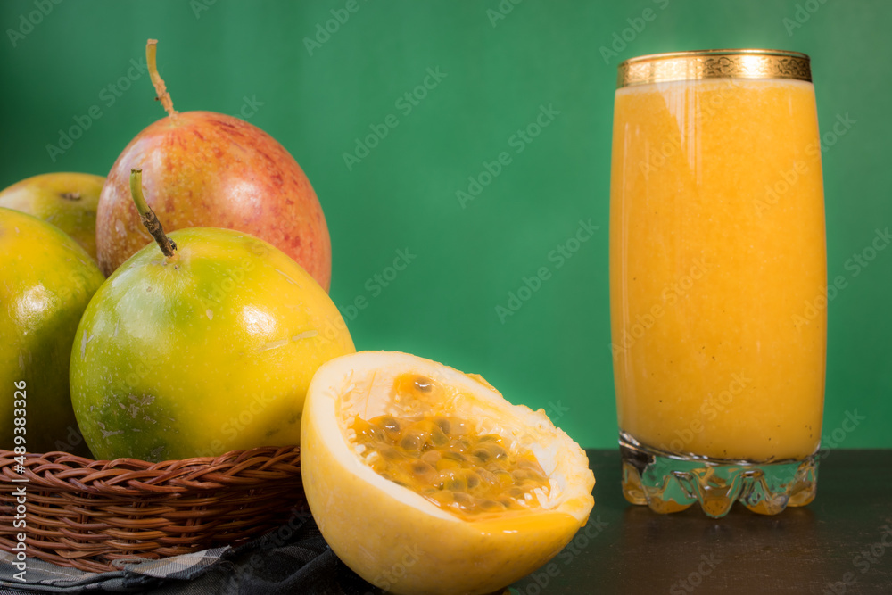Passion fruit in a basket and its juice on a black wooden table with green background Passion fruit in a basket and its juice on a black wooden table with green background