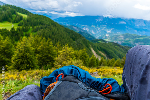 A first-person POV shot of a female hiker sitting with a backpack while it's raining in the French Alps (Valberg, Alpes-Maritimes, France)
