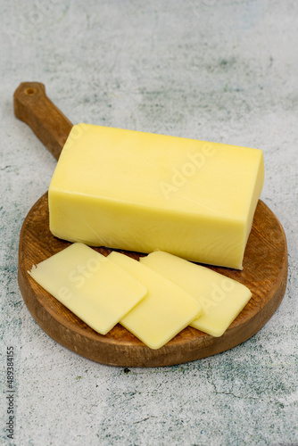 Kashar cheese or kashkaval cheese on stone background. Sliced Cheddar Cheese photo