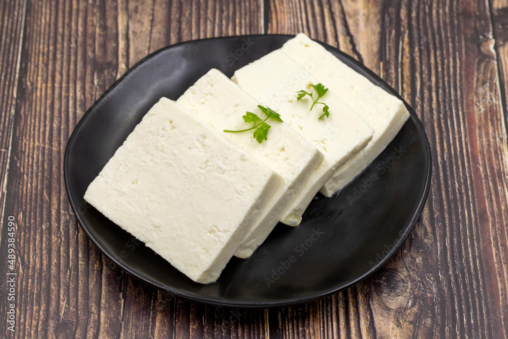 Sliced Feta cheese with herbs on wooden background. Close-up breakfast cheese