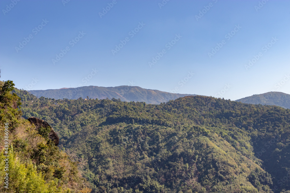 Fototapeta premium mountain covered with green forests and misty blue sky at morning from flat angle