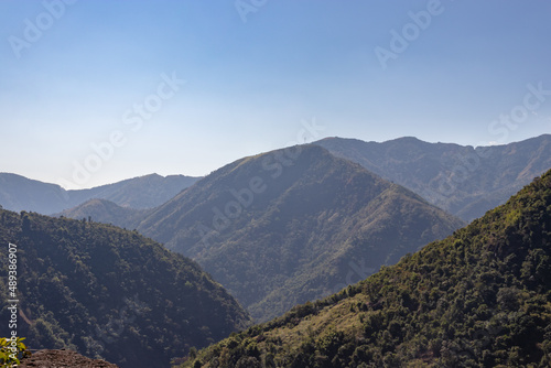 mountain range with green forests and misty blue sky at morning from flat angle