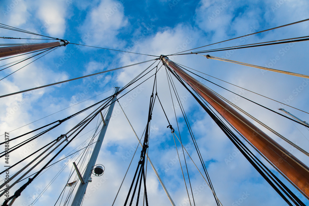 Obraz premium Masts of sailing yachts without sails with anchoring ropes. View from below.