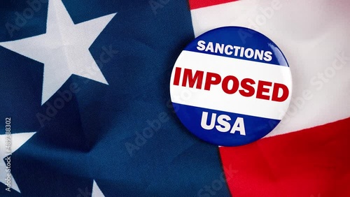 sanctions imposed usa text on campaign button laying on the american flag. Freedom and democracy concept. photo