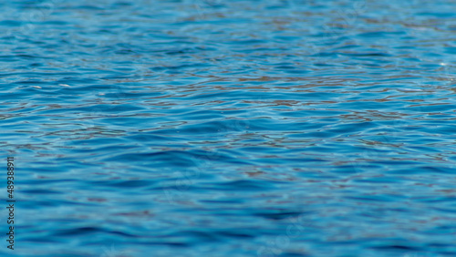 Conceptual cold blue abstract background water. Waves on water, reflection of ripples on the river. Blue water texture.