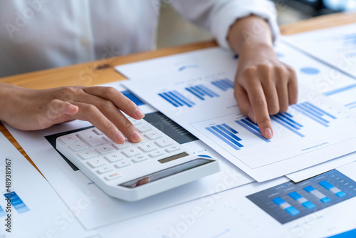 businesswoman working on desk office with using a calculator to calculate the numbers, calculating monthly expenses, tax, managing budget finance accounting concept