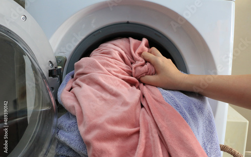 woman hand filling laundry in the washing machine, housewife and hygienic,woman taking color clothes from washing machine. A drum of washing machine full of dirty laundry in home.