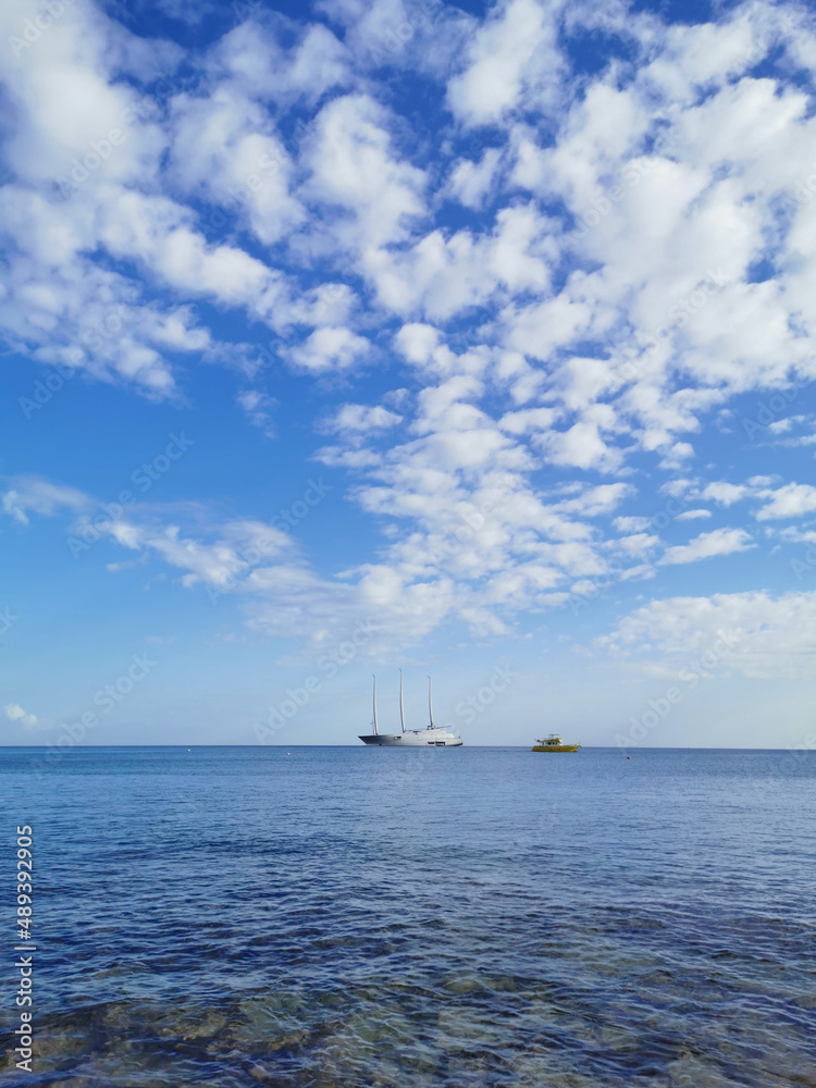 The largest sailing yacht in the world, an eight-deck motorsailer on the Mediterranean coast against a blue sky with beautiful clouds.