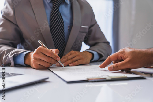 employer interviewing for a job or head of HR is reading a resume while discussing the job applicant's resume. An employer in a suit is interviewing for a job. Hire a Resource Manager and recruiting