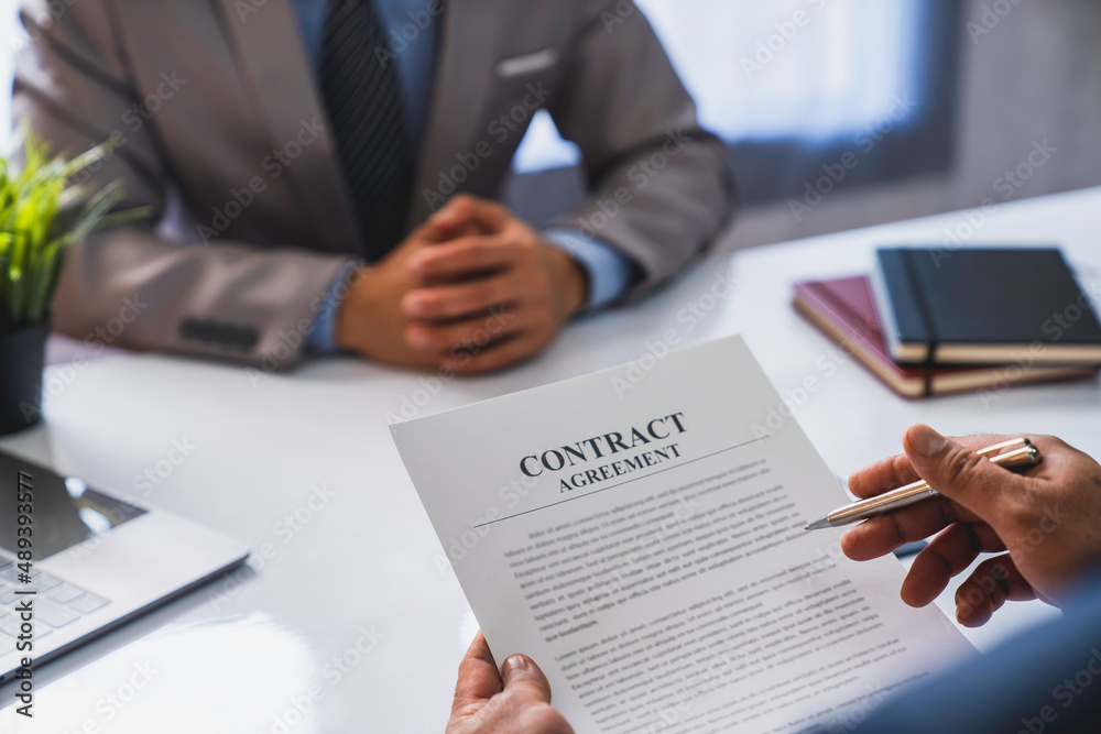 An employer interviewing for a job or head of HR is reading a resume while discussing the resume. An employer in a suit is interviewing for a job. Hire a Resource Manager and recruiting concept An employer interviewing for a job or head of HR is reading a resume while discussing the resume. An employer in a suit is interviewing for a job. Hire a Resource Manager and recruiting concept