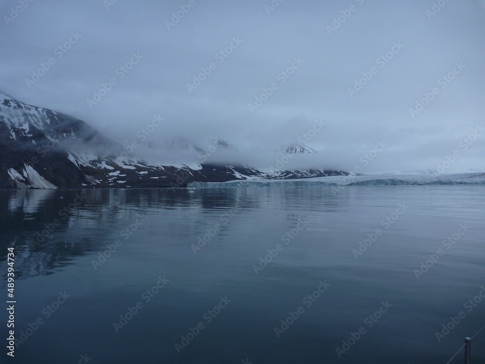 malownicze ośnieżone góry we mgle odbijające się w tafli wody w regionie svalbard na arktyce - obrazy, fototapety, plakaty 