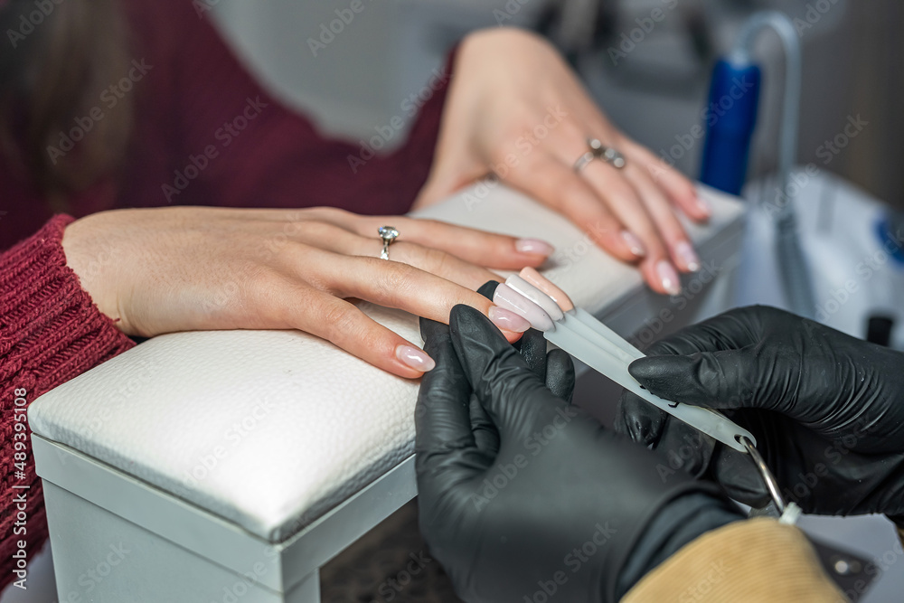 Fototapeta premium Close up of a young brunette trying to choose the right color of nail polish in a beauty salon