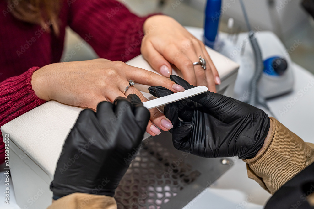 the manicurist  gloves holds the client's hand and works with it during the epidemic.