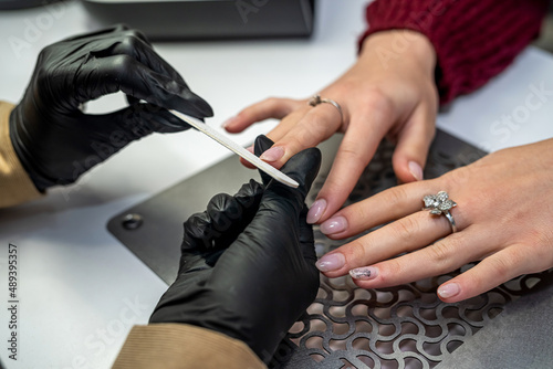 the manicurist  gloves holds the client s hand and works with it during the epidemic.