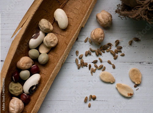 Assorted seeds on a whitewashed wooden table including bean, pea, pumpkin, anise, bald cypress 