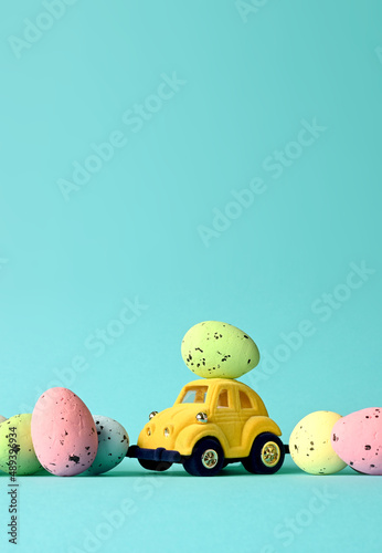 Photography One Easter egg on a small car on a blue background. Copy space.