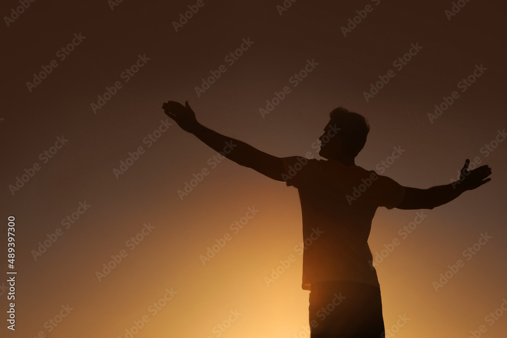 Surrendering to a higher power. Silhouette of a man with his arms outstretched - copyspace.