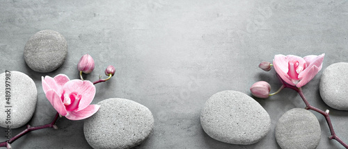 Photography Flat lay composition with spa stones, orchid pink flower on grey background