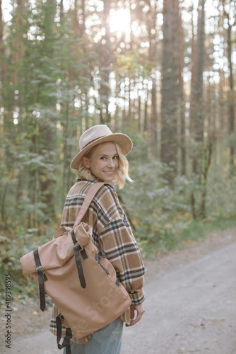 Portrait of attractive young woman wearing hat hiking in the forest. Travelling concept.