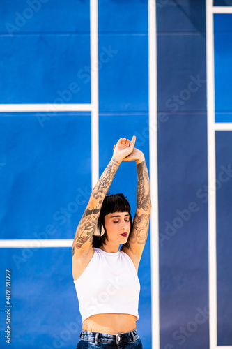 Una mujer caucásica con tatuajes y pelo corto escuchando música con unos auriculares en una pista deportiva 
