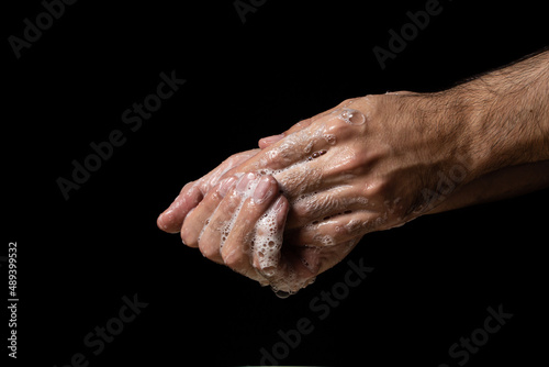 Washing hands with soap on a black background. Personal hygiene and health care.