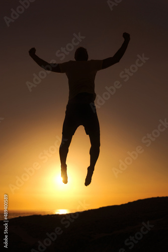 Free and in tune with the world. Silhouette of a man jumping in the air with the sunset in the background.